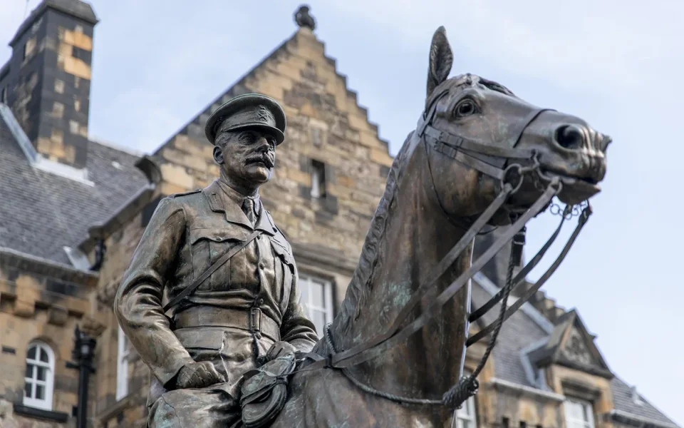 Mounted military statue beside historic stone buildings at Edinburgh Castle