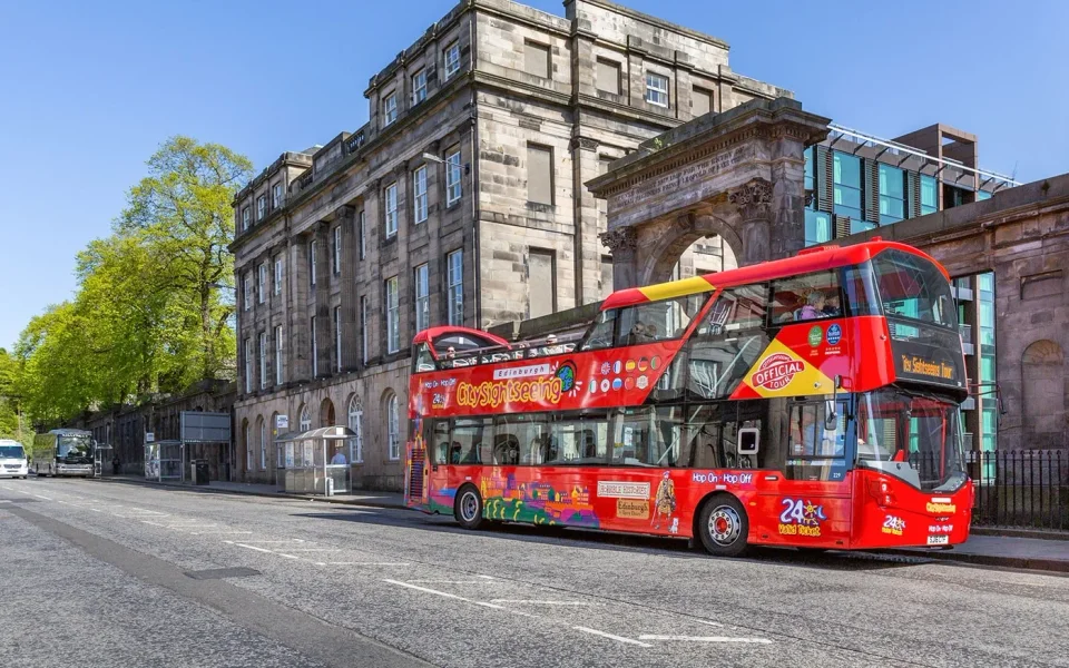 Open‑Top‑Sightseeing-Bus vor einem steinernen Gebäude in Edinburgh