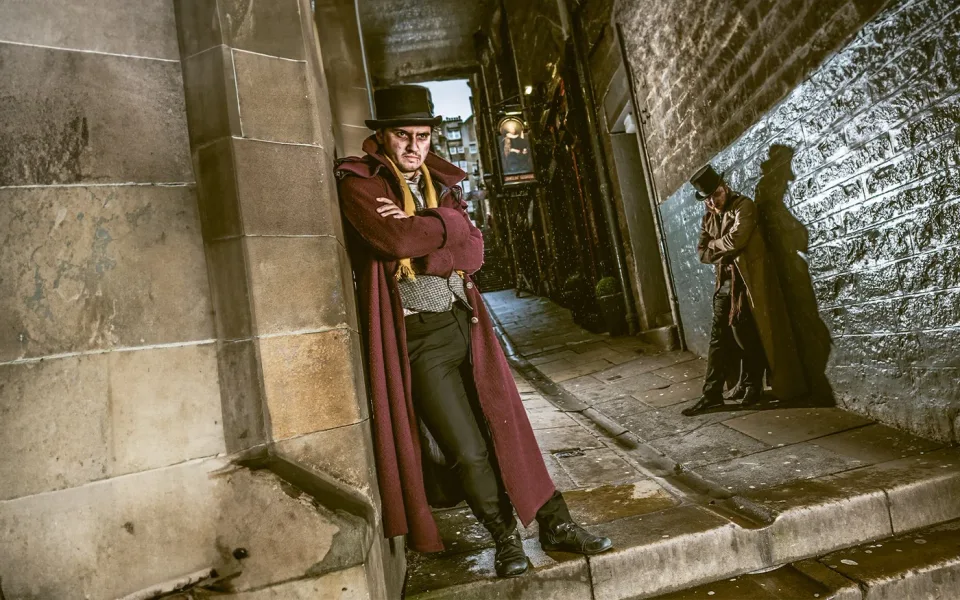 Costumed performer beside a stone entrance at the Edinburgh Dungeon