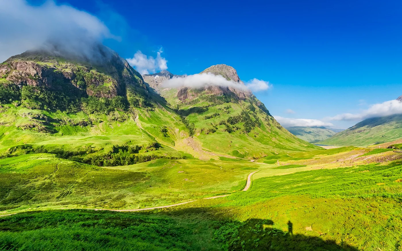Green Highland valley beneath mountains and cloud