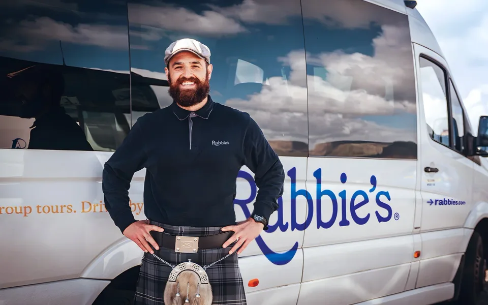 Driver-guide beside a Highland tour vehicle